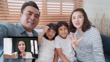 Video görüşmesi yapan genç Asyalı bir aile, evde uzaktan kumandalı bir toplantı, kameraya bak. İnternet iletişim teknolojisi, insanlar yaşam tarzını veya koronavirüs sosyal mesafeleme kavramını bağlar