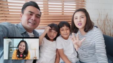 Video görüşmesi yapan genç Asyalı bir aile, evde uzaktan kumandalı bir toplantı, kameraya bak. İnternet iletişim teknolojisi, insanlar yaşam tarzını veya koronavirüs sosyal mesafeleme kavramını bağlar