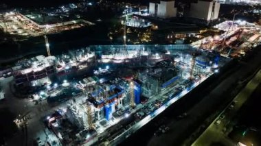 Gece Asya 'da inşaat alanı projesi, vinç ve araba trafiği ulaşımının hızlandırılması. Hava aracı görüntüsü. Sanayi veya inşaat mühendisliği teknolojisi kavramı