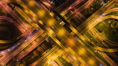 Gece Asya 'da birden fazla şeritten ya da otobandan geçen araç trafiğinin hızlandırılmış sürati, insansız hava aracı üst görüntüsü yukarı doğru uçuyor. İnşaat mühendisliği, Asya ulaşım konsepti