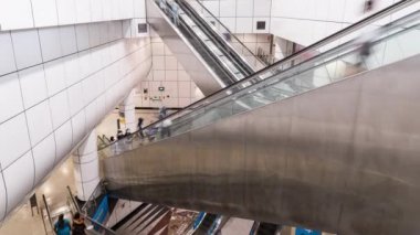 Asyalılar Singapur 'daki MRT metro istasyonunda yürüyen ve yürüyen merdiven kullanıyor. Toplu taşıma, Asya günlük şehir hayatı, ya da banliyö yaşam tarzı konsepti. Eğil.