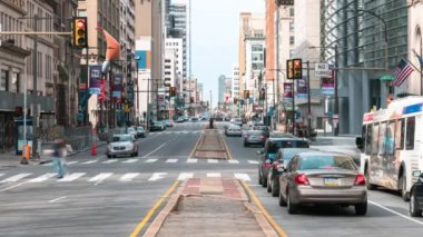 Downtown cityscape time-lapse of car traffic transportation, people walk cross road at junction intersection in Philadelphia, USA. Public transport, American city life, or commuter lifestyle concept