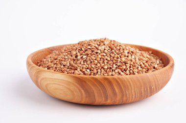 Çiğ karabuğday beyaz arka planda ahşap bir kasede inliyor.