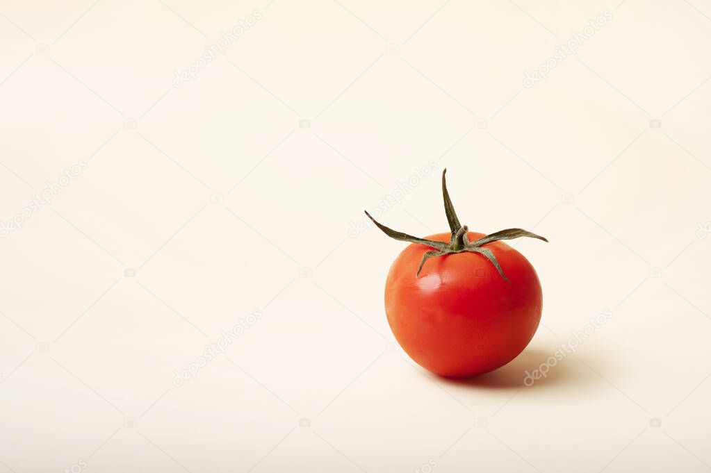 ripe red tomato on a light yellow background