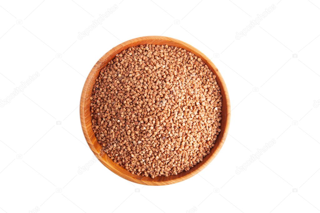 Dry buckwheat groats in a wooden bowl on a white background top view