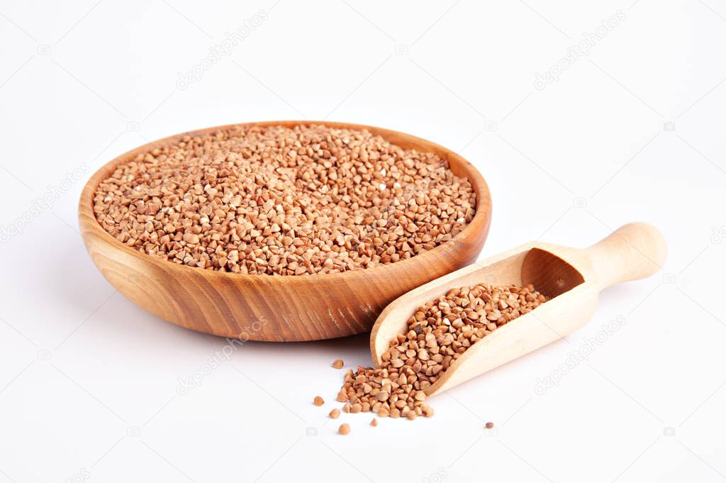 Dry buckwheat groats in a wooden bowl with a wooden scoop with groats near