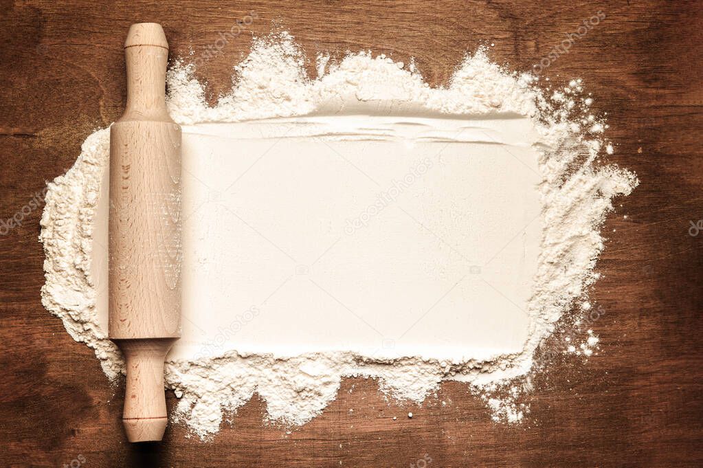 flour and rolling pin on the brown wood background