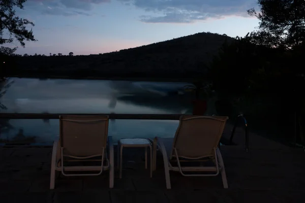 Chairs in front of infinity pool with lake and mountain views at dawn between dusk and dawn in Mexico