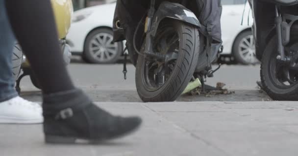 Piso de rua de movimento lento pan de calçada mostrando pés de pedestres, rodas de scooter e tráfego. Foco seletivo — Vídeo de Stock