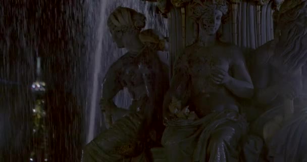 Szczegóły posągów, woda w kamiennej fontannie w nocy z oświetloną musującą wieżą w tle. — Wideo stockowe
