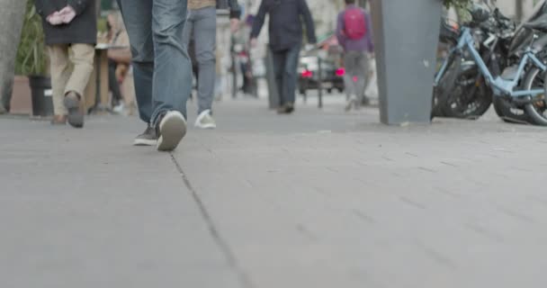 Vista de las piernas de tres hombres jóvenes caminando en la acera con otros peatones, pan de cámara lenta a la pared gris. Enfoque selectivo — Vídeos de Stock