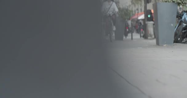 A corrediça revela da parede cinzenta à vista do nível do solo da calçada com a mulher nova na bicicleta que monta para a câmera. Movimento lento, profundidade de campo rasa. — Vídeo de Stock