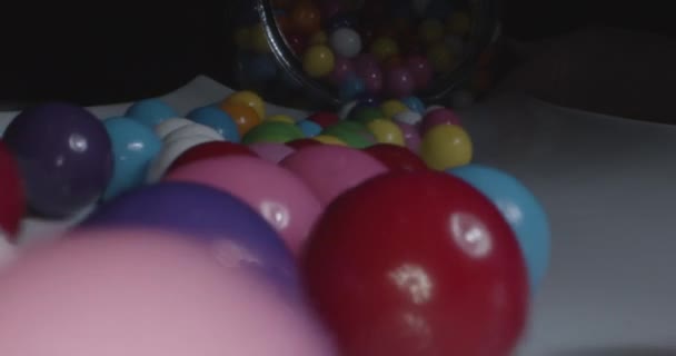 Extreme close up πολύχρωμα gumballs χυθεί έξω από ένα βάζο σε λευκό πιατέλα σε πραγματικό χρόνο με ήχο — Αρχείο Βίντεο