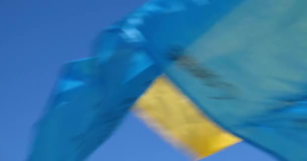 Закрийте прапор України, розмахуючи вітром на українській мітингу з синім небом. — стокове відео