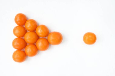 Sarı domatesler beyaz bir masaya ok şeklinde ve sarı bir domatesin yanına istiflenir.