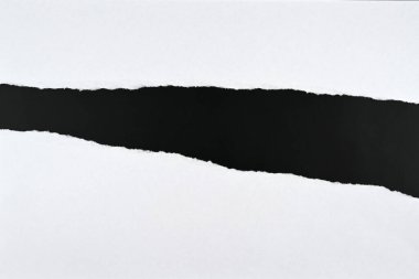 Ortası beyaz bir kağıttan yırtılmış ve siyah bir masa görünür hale gelmiş. Düz yat, üstten bak, kapat, makro