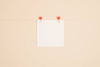 Paper card attached to a thread with wooden heart shaped clothespins. Valentine's Day or any other love invitation cards.