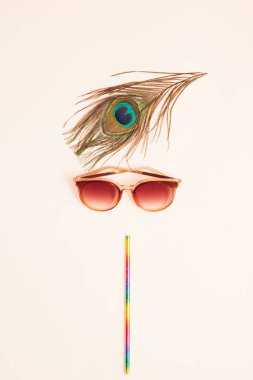 Güneş gözlüklerinden, tavus kuşu tüyünden ve renkli pipetten yapılmış yaratıcı kız yüzü. Asgari güzellik ya da yaz konsepti. Düz yatıyordu.
