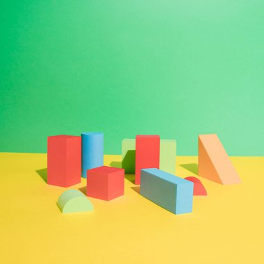 Sarı ve yeşil zemin üzerinde renkli geometrik nesneler kümesi. Şekil ve şekle göre soyut şablon tasarımı. Eğitim, iş çözümü, yaratıcı tasarım ürünü kavramı.