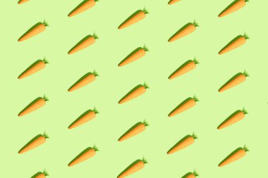 Pastel yeşil arka planda havuç. Paskalya tatili konsepti. Minimum bileşim. Kusursuz desen, izometrik görünüm.