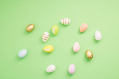 Pastel yeşil arka planda renkli Paskalya yumurtalarından yapılmış desen. Asgari Paskalya veya gıda konsepti.