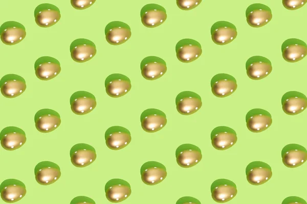 パステルグリーンの背景に黄金の卵で作られたパターン 最小限のイースターまたはフードコンセプト — ストック写真