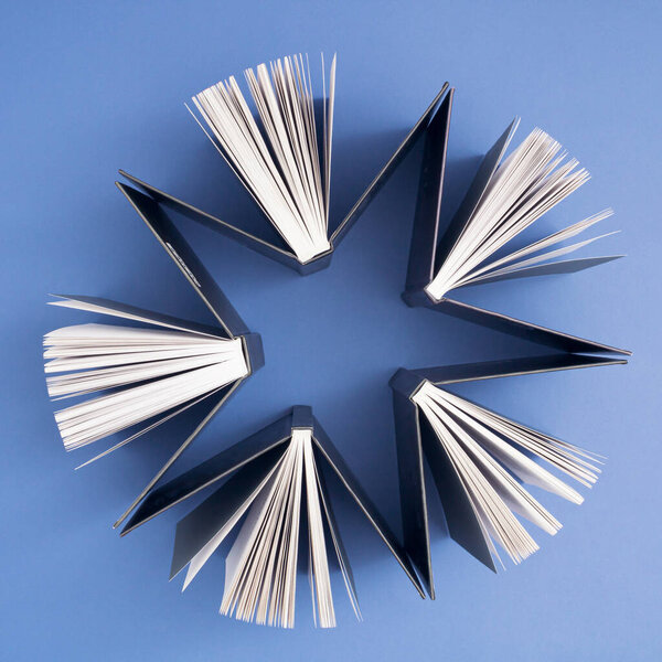 Books form a shape of star on blue background. Education, knowledge or Nature concept. Flat lay.