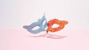 Pastel pembe arka planda Venedik kırmızı ve mavi karnaval maskesi. Duygular, aşk, duygular veya Karnaval, Maskeli Balo konsepti. Duygusal Öpücük.