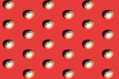 Kırmızı zemin üzerinde altın yumurtadan yapılmış desen. Asgari Paskalya veya gıda konsepti.