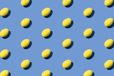 Mavi arkaplandaki sarı yumurtalardan yapılmış desen. Asgari Paskalya veya gıda konsepti.