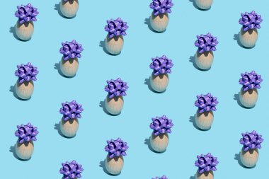 Paskalya yumurtalarından yapılmış kusursuz desenli mavi arka planda şenlikli mor bir fiyonk. Tatil konsepti. Boşluğu kopyala.