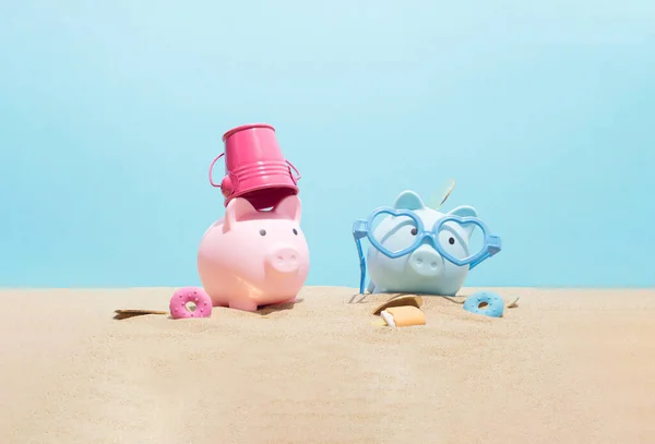 Pink and blue piggy banks with sunglasses relax on the beach. Travel money savings concept.  Summer vacation, holiday composition.