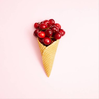 Pastel pembe arka planda kirazla dolu dondurma külahı. Waffle külahında taze kiraz. Yaz konsepti.