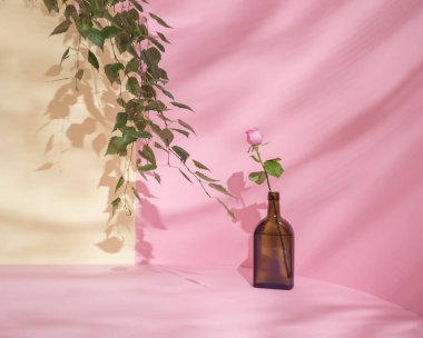 Pembe güllü güzel bir retro kahverengi şişe. Ebedi estetik, ev dekorasyonu fotoğrafçılık tarzı. Dergiler veya Akdeniz tarzı.