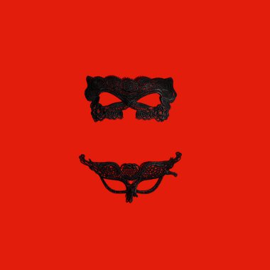 Two sexy black Venetian masks on vibrant red background. Love, underwear or Carnival, Masquerade concept.