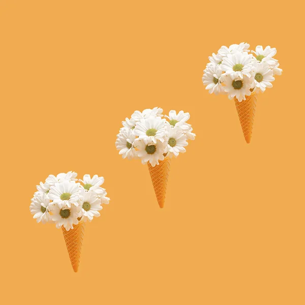 Chamomile daisy flowers in an ice cream waffle cone against sunshade orange  color background. Aesthetic floral scene.