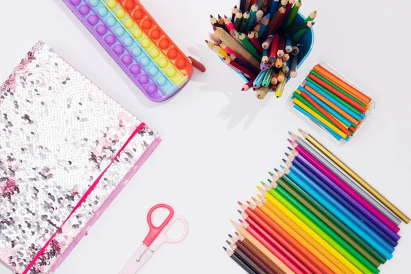 Pop it pencil case, pencils, textbook and colorful material for creativity.  Back to School concept. Flat lay. Rainbow color