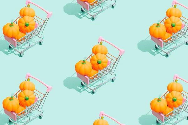 Halloween festival shopping concept. Little pumpkins with shopping cart on  green background. Aesthetic Thanksgiving or Halloween composition in a minimalist style, trendy colors.