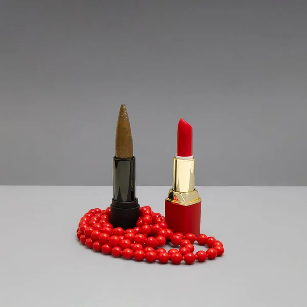 Red lipstick,  bullet and vibrant red pearl necklace in line. Feminine background for huntress or woman soldier.