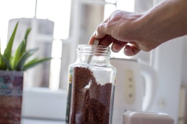 Bir adam, yorucu ve verimli bir gün için sabahları kendine kahve yapar.