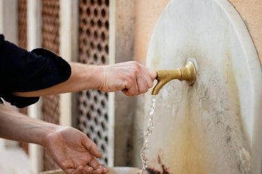 İtalya, Roma 'da antika bir çeşme. Bir adam ellerini yıkar.