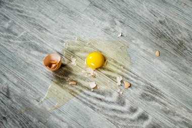 Broken egg on the floor with copy space. Selective focus. This photo can be used for the concept of how to clean up the dropped eggs. clipart