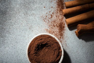 Seylan tarçın çubukları ve tarçın kasesi. Arkaplanda dikkatsizce dağılmış tarçın var. Üst görünüm