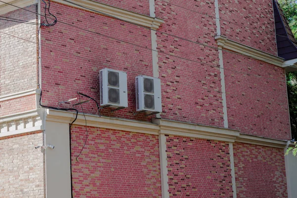 Air conditioning fans outside a private brick building.