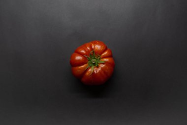 Tomato, red tomato on isolated black background, top view photo, fruit concept idea photo.