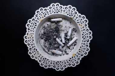 Cigarette butts, cigarette butts in white ashtray on black background, isolated photo, top view photo.