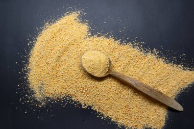 Tarhana and wooden spoon isolated on black background, scattered tarhana grains, Turkish food concept idea photo, top view photo.