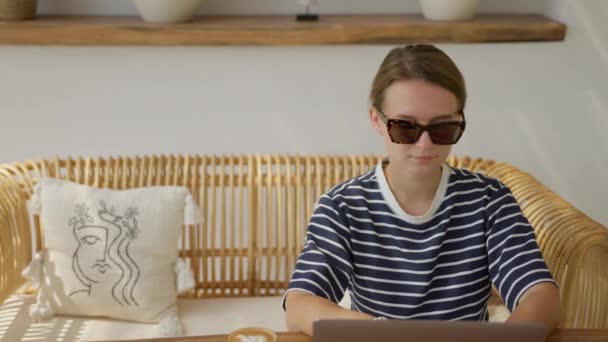 여자가 안경을 테이블에 커피를 마시면서 노트북 컴퓨터로 일하고 — 비디오