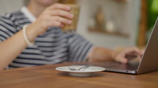 Улыбающаяся Молодая Женщина Очках Работающая Ноутбуком Выпивая Кофе Сидя Столом — стоковое видео
