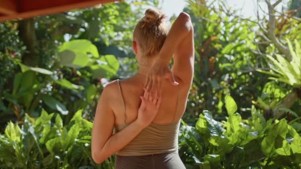 妊娠中の女性は庭を背景に自宅でヨガポーズをし 彼女の腹を受け入れます 夏の日差しの波 — ストック動画